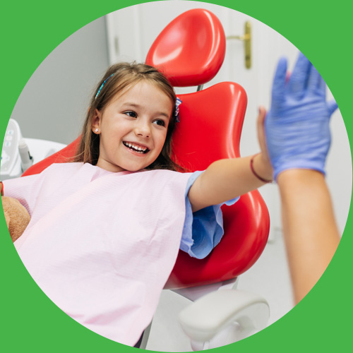 Girl on dental chair giving dentist a high five